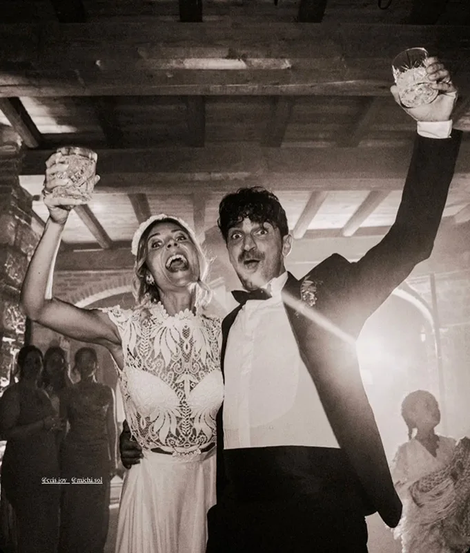 Sposi che brindano al ricevimento: abito da sposa in pizzo, fotografia in bianco e nero