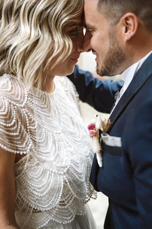 Sposa e sposo fronte contro fronte: abito da sposa a due pezzi con top ricamato a perline