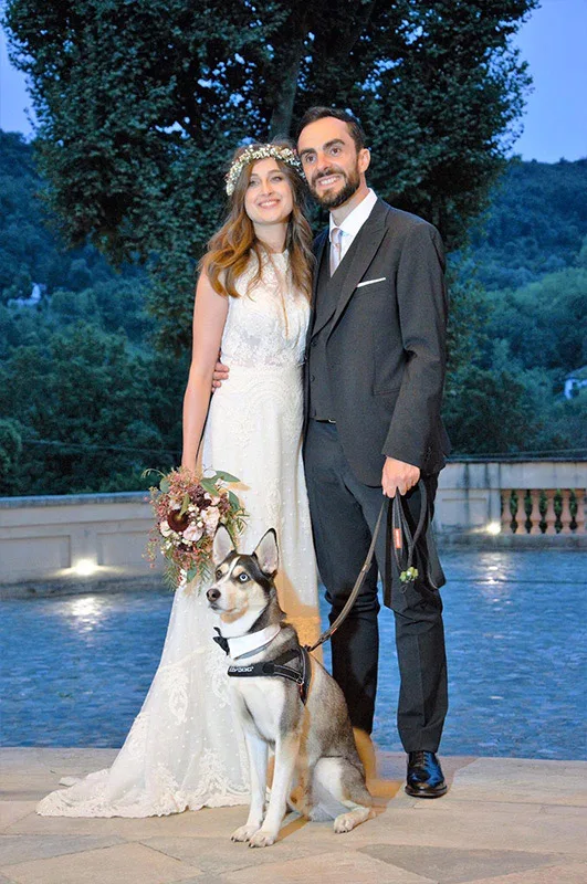 Sposi al crepuscolo con il loro cane: abito da sposa ricamato e coroncina di fiori