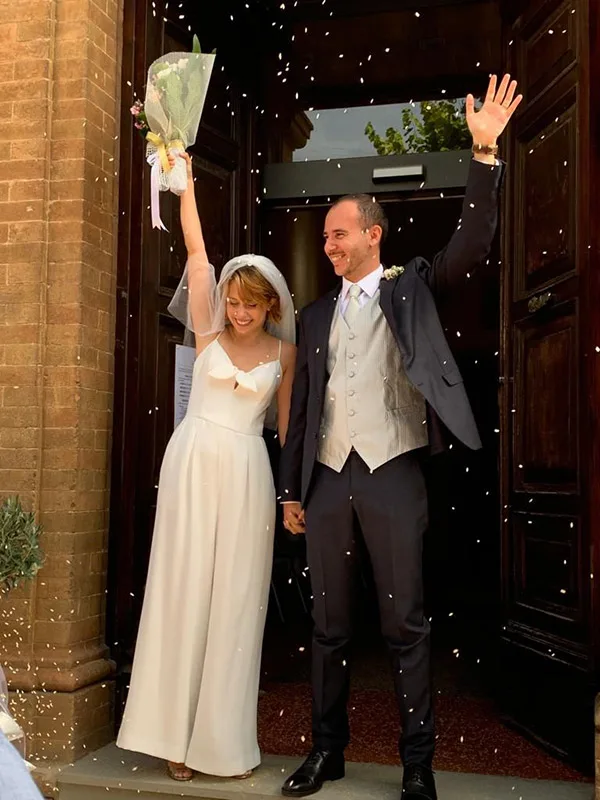 Sposa in tuta da sposa e velo all’uscita dalla chiesa, sotto il riso