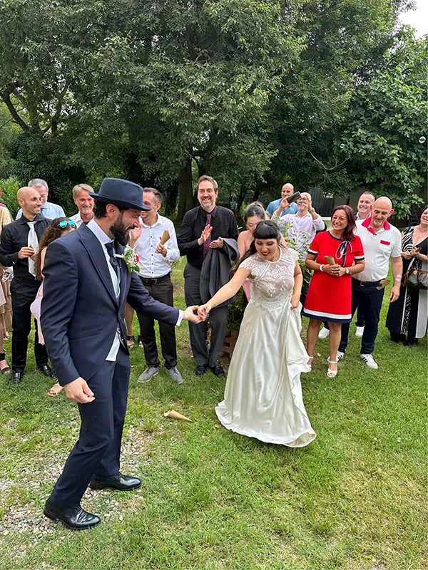 Sposi che ballano circondati dagli invitati: abito da sposa dal taglio retrò