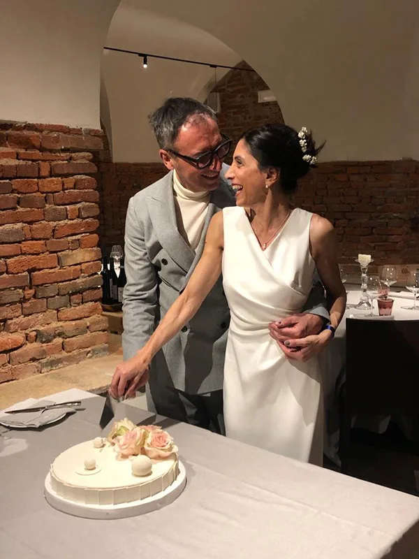 Sposi tagliano la torta: abito da sposa minimal in raso, senza maniche